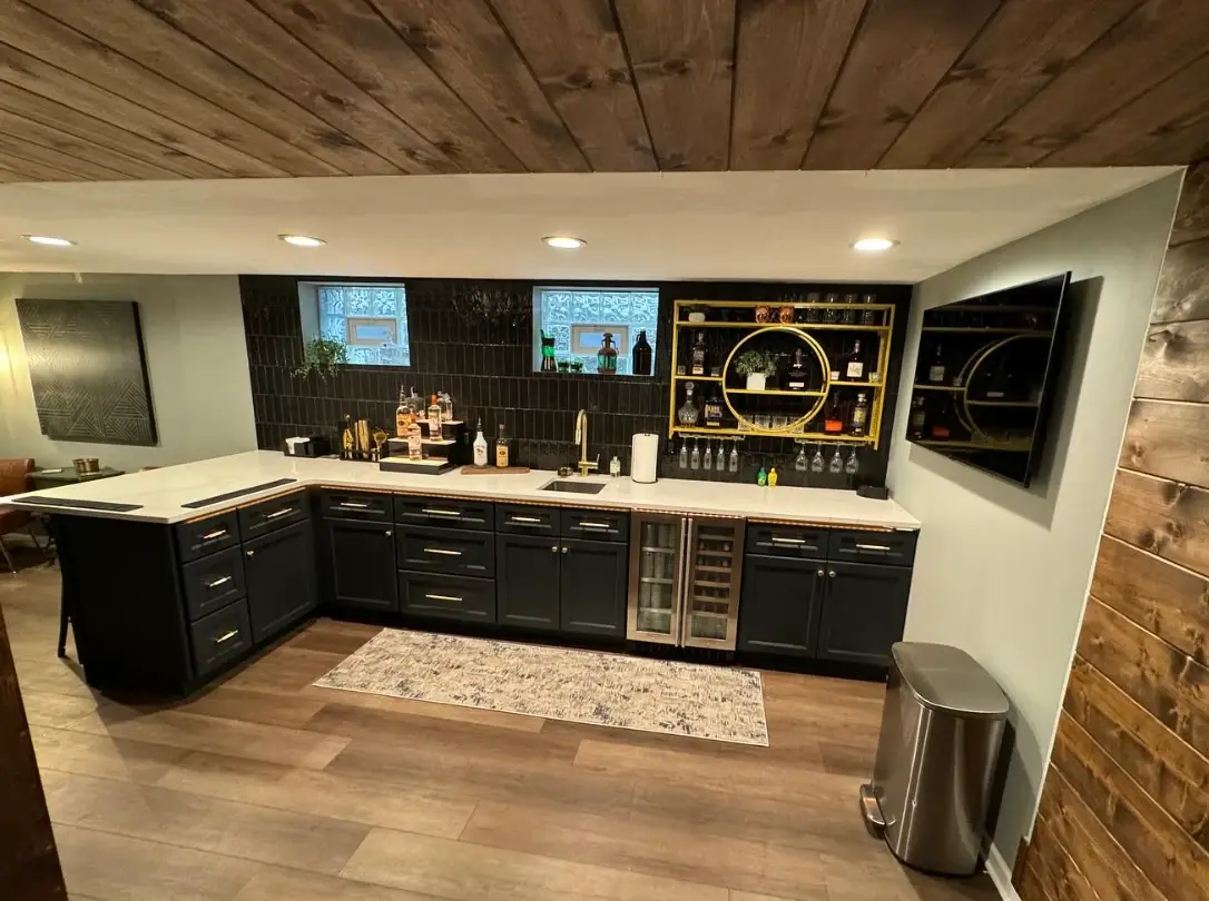 Full basement bar with black tile, gold shelving, quartz counters, and a wine fridge