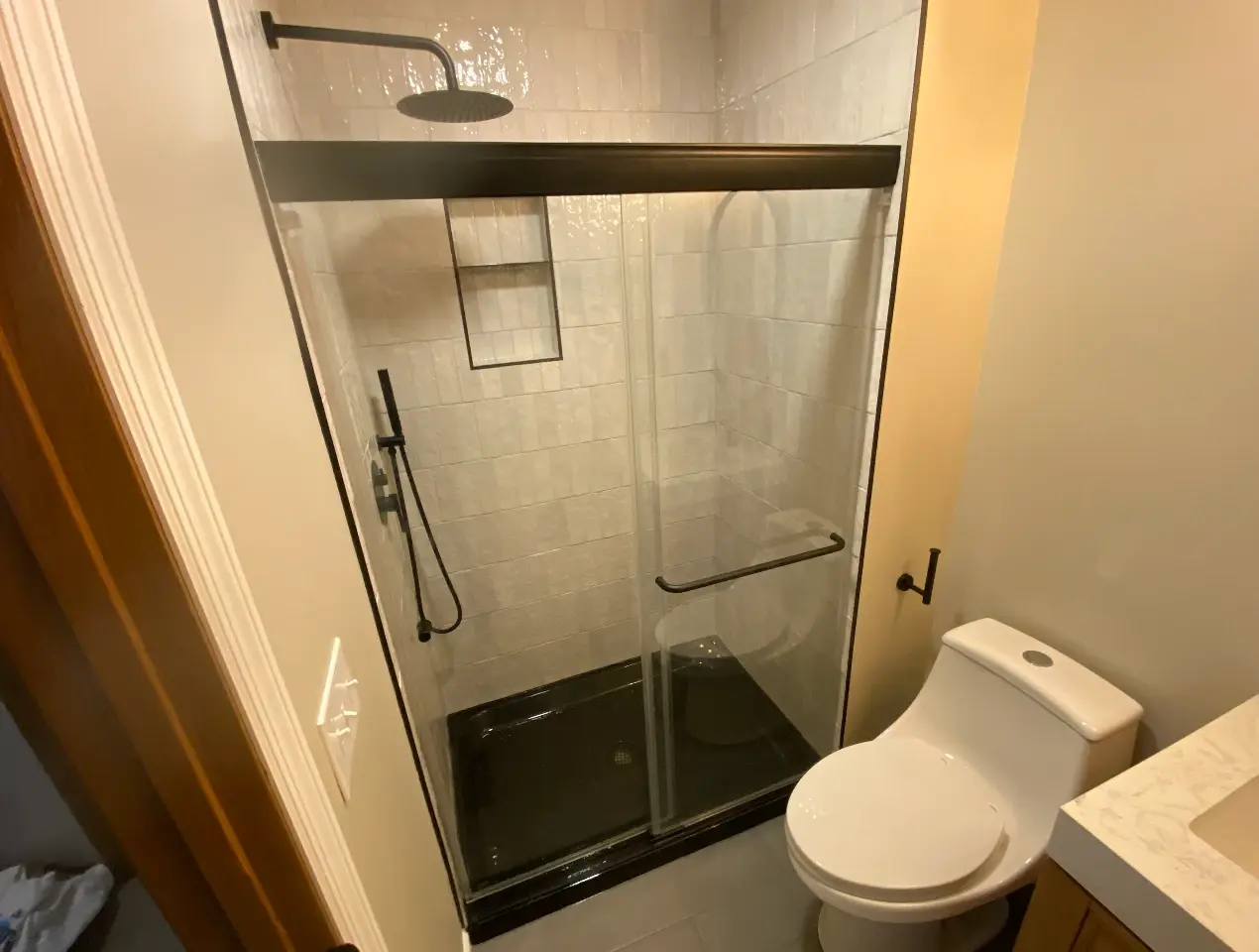 Basement bathroom after, glass shower with white tile and matte black fixtures