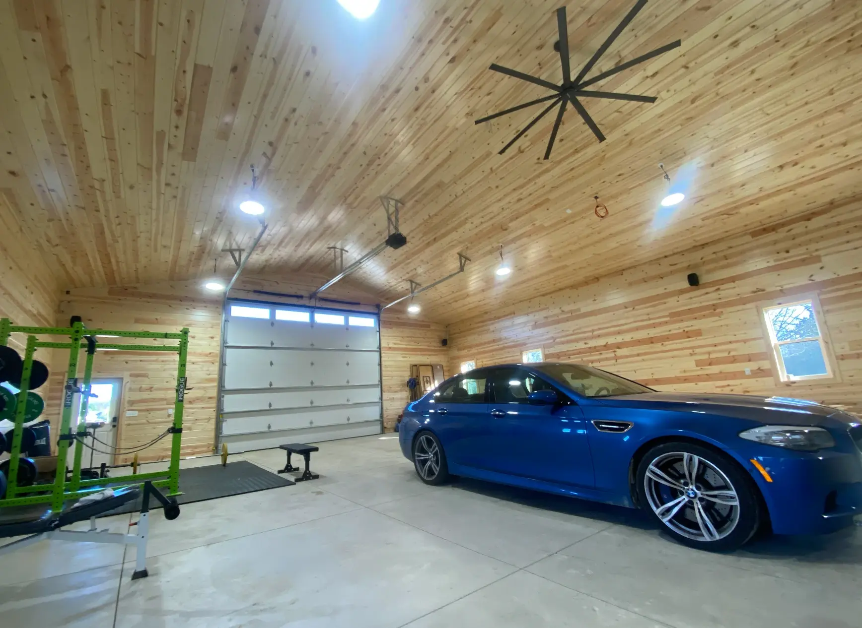 Pole barn garage after, fully paneled in knotty pine with a ceiling fan and finished floor